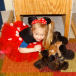 A little girl in minnie mouse costume with several cats.